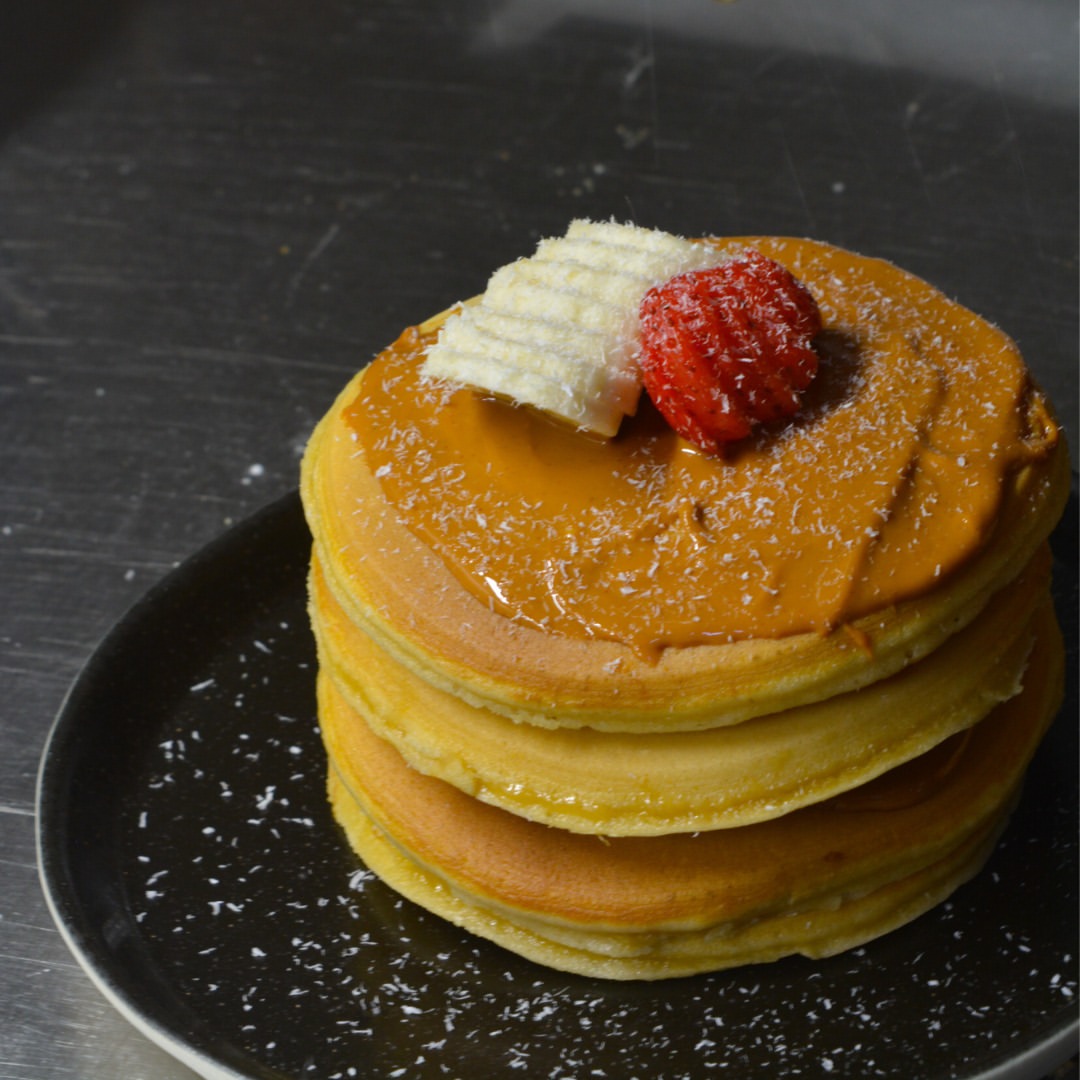 Pilha de panquecas com fruta e cobertura dourada