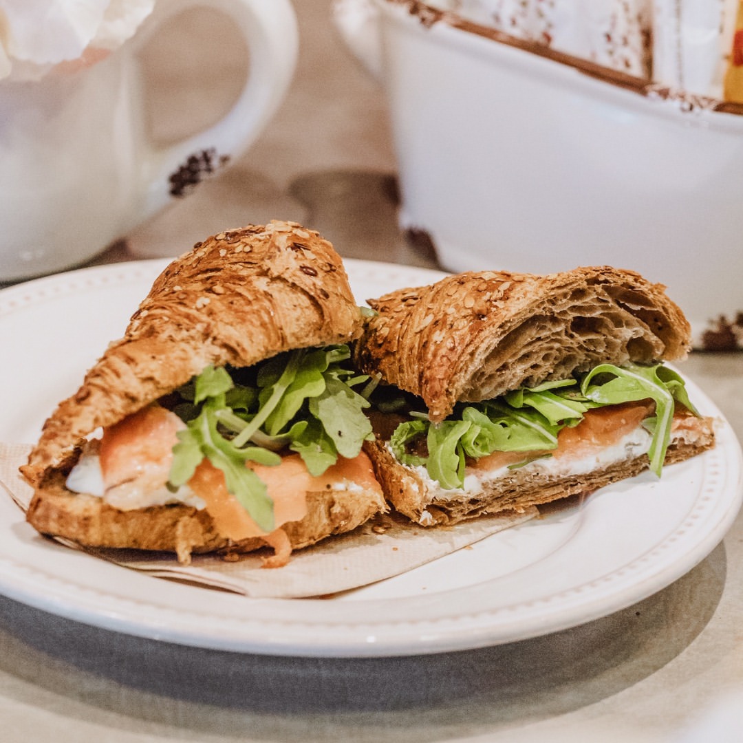 Croissant recheado com fiambre e salada sobre prato branco